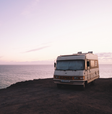 recreational vehicle parked by cliff at ocean